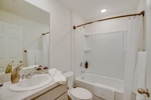 Bathroom features a sink, toilet, and bathtub with a shower curtain.