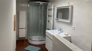 Une salle de bain moderne avec une douche à parois de verre, un lavabo blanc et un miroir au-dessus.