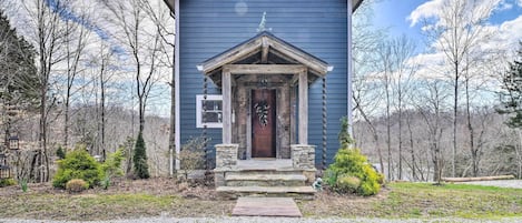 A small, single-story building with a dark blue exterior, a wooden front door, and a small porch with stone steps.