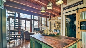 A rustic interior with a wooden bar, a spiral staircase, and a welcoming sign.