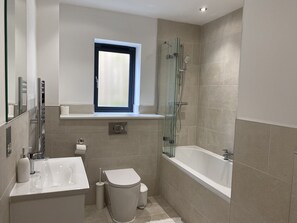 A modern bathroom with a bathtub, a glass-enclosed shower, a toilet, and a sink. - Galwad y Mor (Haverfordwest)