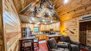 Interior acogedor de una cabaña con paredes de madera, una zona de cocina y asientos.