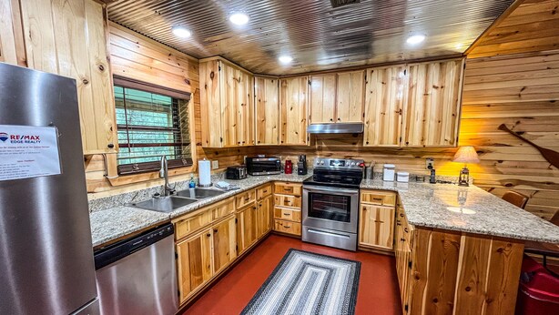 Una cocina moderna con armarios de madera, electrodomésticos de acero inoxidable y una alfombra roja.