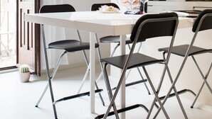 A modern kitchen with a white table, black chairs, and a pendant light. - Suite La Piazza by Wonderful Italy (Syracuse)