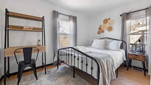 Une chambre à coucher comprenant un lit, un bureau avec une chaise, une fenêtre avec des rideaux et des éléments de décoration murale.