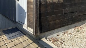 Een gebouw met een witte deur, een raam en een houten terras.