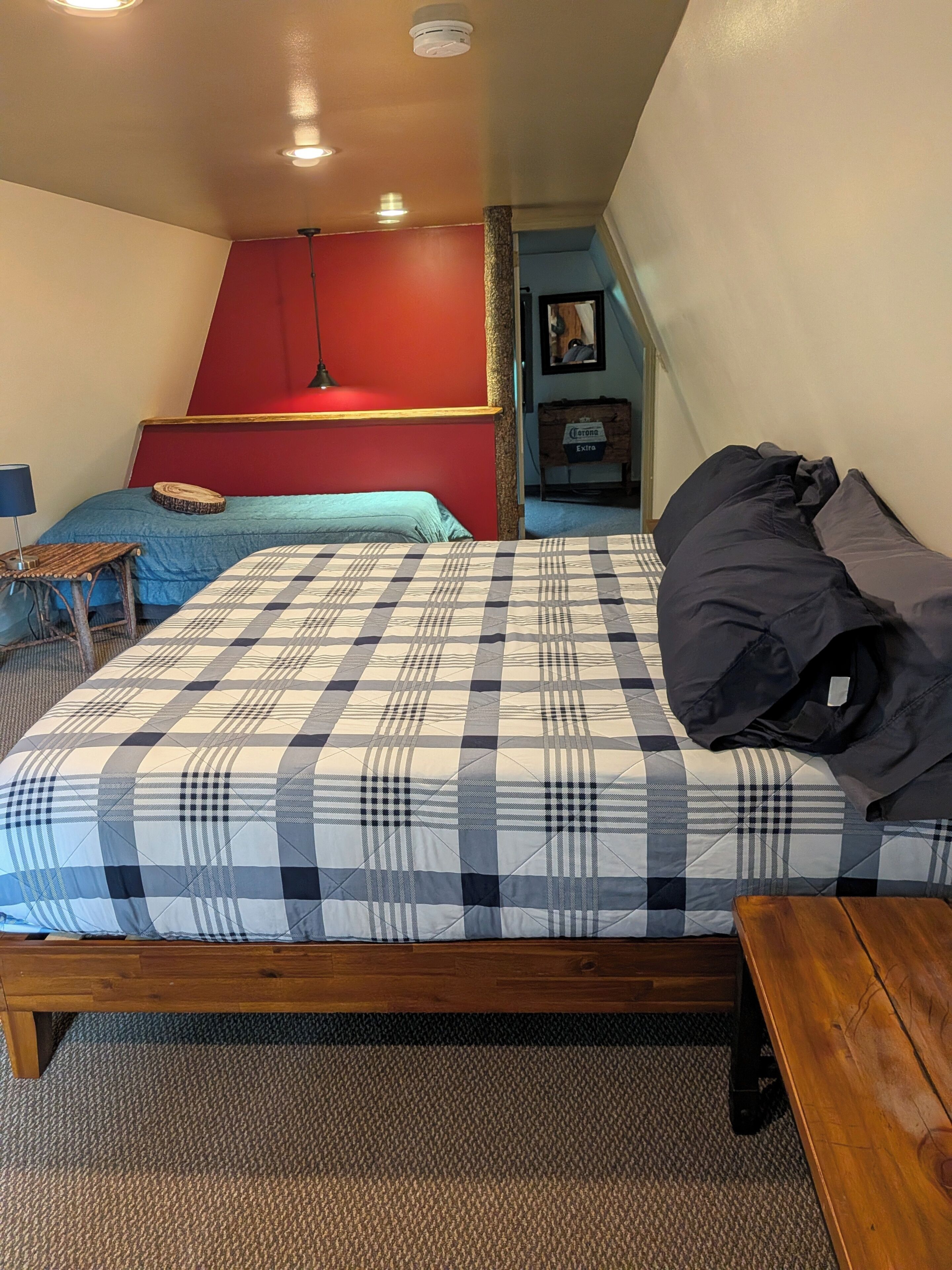 A bedroom with a bed, a wooden bench, a small table, and a red wall.