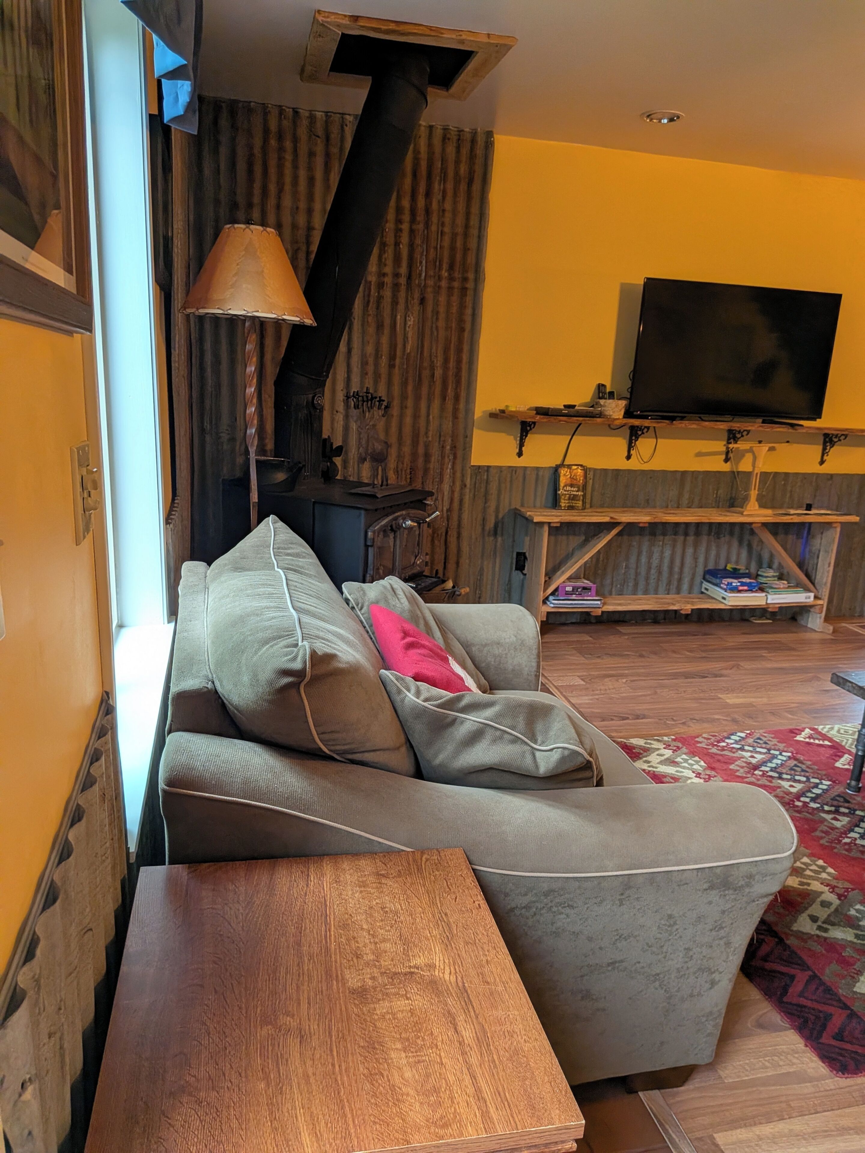 A living room with a sofa, a wooden table, a fireplace, a television, and a patterned rug.