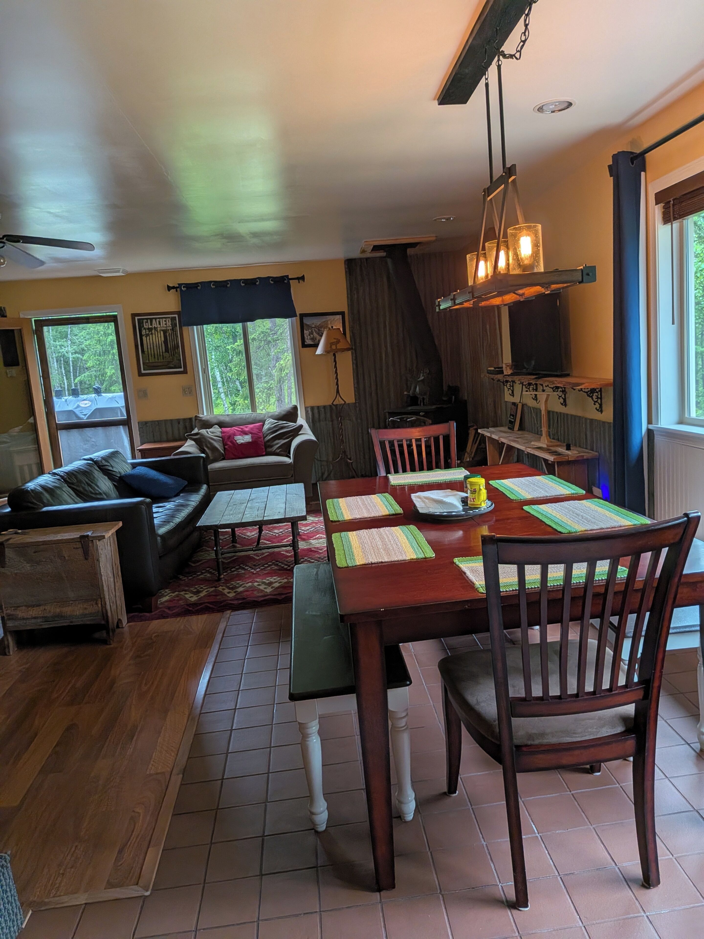 Una sala de estar acogedora con un sofá, una mesa de comedor con individuales y un televisor sobre un mueble.