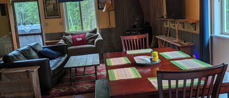 Una sala de estar acogedora con un sofá, una mesa de comedor con individuales y un televisor sobre un mueble.