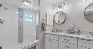 A bathroom with a shower, toilet, sink, and mirror.