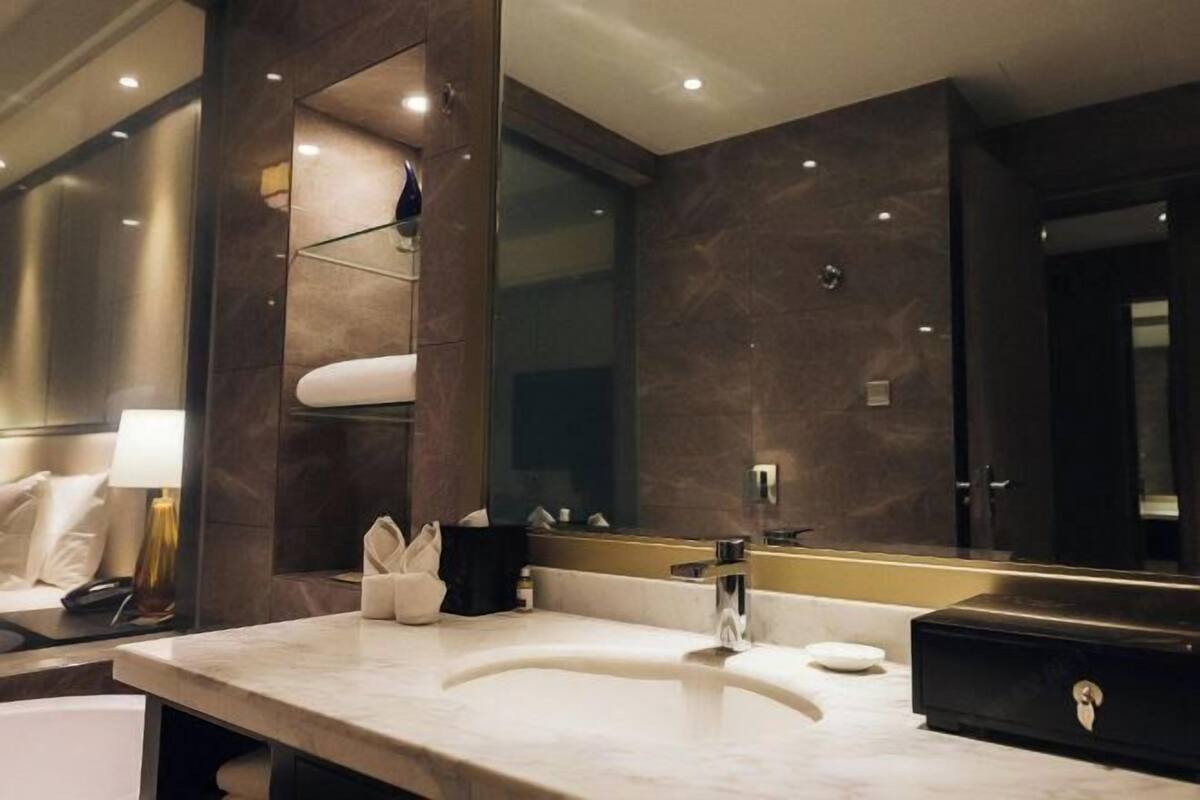 A modern bathroom with a marble sink, a large mirror, and a dark-toned wall.