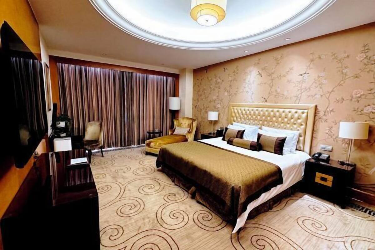 A hotel room with a large bed, a TV, a desk, and a chair.