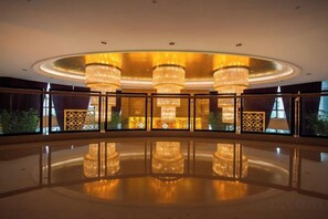 A spacious lobby with a reflective floor, large chandeliers, and a view of the outdoors. - Binjiang International Hotel (Tengzhou)