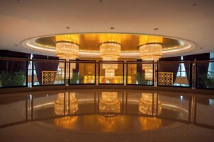 Un vestíbulo amplio con suelo reflectante, grandes candelabros y vistas al exterior.
