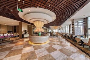 A hotel lobby with a check-in counter, seating area, and a central decorative fountain. - Binjiang International Hotel (Tengzhou)