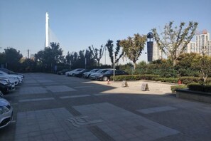 Ein Parkplatz mit mehreren Autos, blauem Himmel und einem hohen, weißen Turm im Hintergrund.