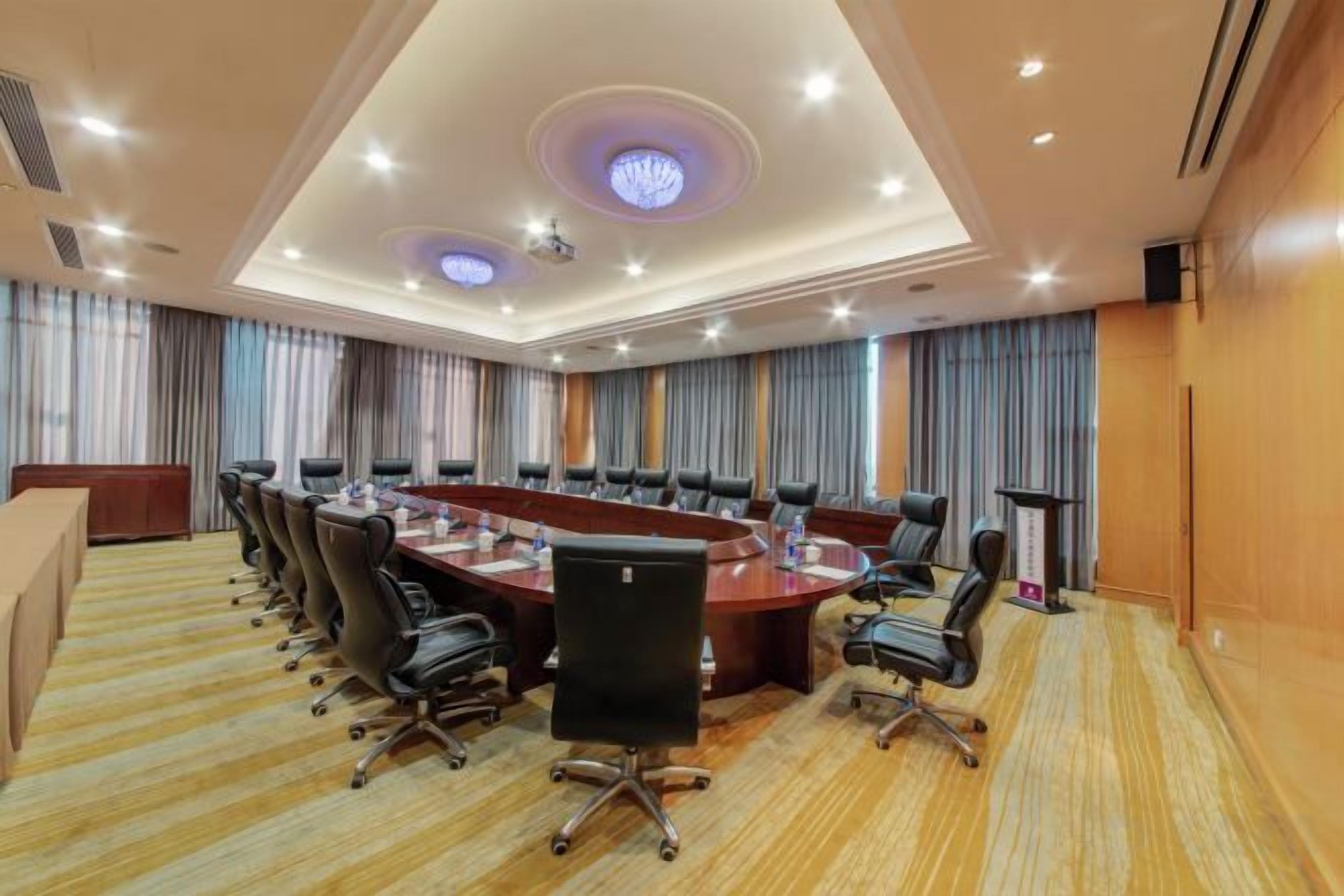 Una sala de conferencias con una larga mesa, sillas y piso alfombrado.