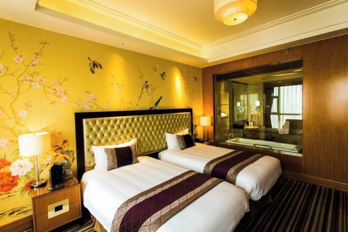A hotel room with two beds, a large mirror, and a nightstand with a lamp.