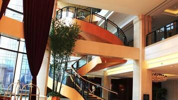 A multi-level interior with a spiral staircase, large windows, and indoor plants.