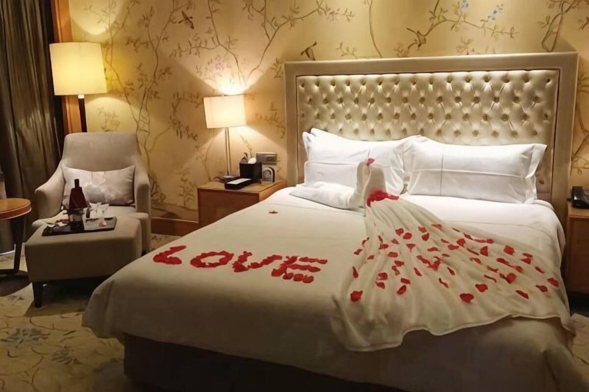 A hotel room with a bed, a chair, a nightstand, and a lamp.
