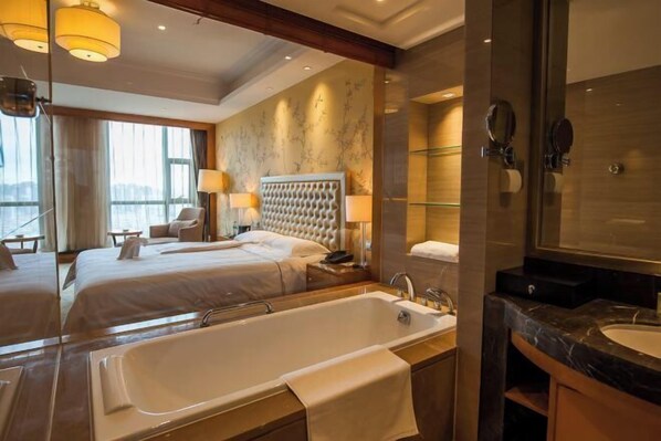 A hotel room with two beds, a large bathtub, a separate bathroom with a mirror, and a view of the outdoors. - Binjiang International Hotel (Tengzhou)