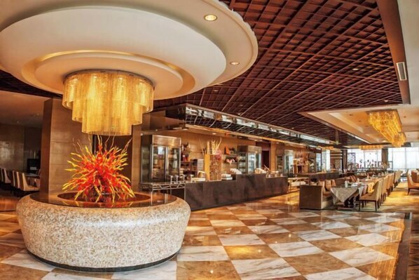 A modern lobby with a circular seating area, a central decorative plant, and a checkered floor. - Binjiang International Hotel (Tengzhou)