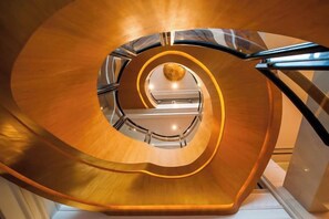 A spiral staircase with a central glass railing and a polished wooden finish. - Binjiang International Hotel (Tengzhou)