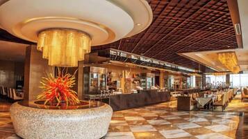 A spacious lobby with a checkered floor, a central decorative fountain, and a modern ceiling design.