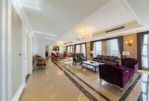A spacious hotel lobby with a long corridor, a seating area with a sofa and chairs, and a chandelier. - Binjiang International Hotel (Tengzhou)