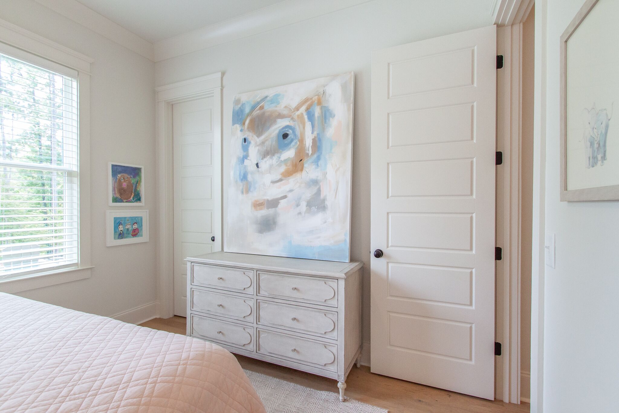 A bedroom with a bed, a dresser, and a large abstract painting on the wall.