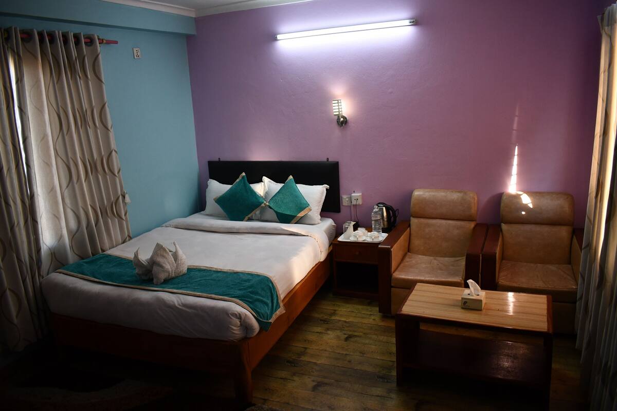 A hotel room with a bed, a nightstand, a chair, and a table.