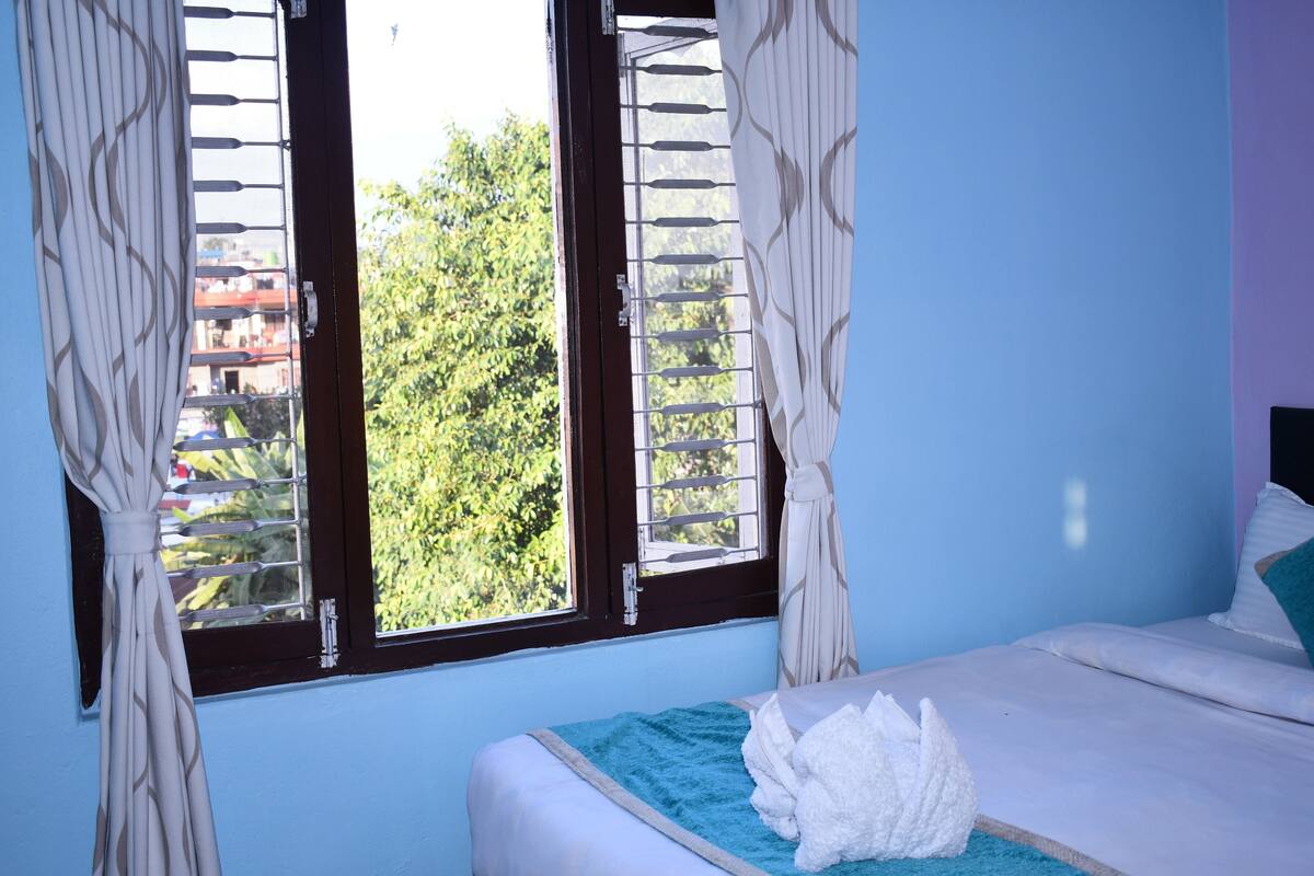 A bedroom with a bed, curtains, and a window with blinds.