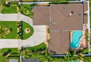 An aerial view of a residential property with a swimming pool, a driveway, and landscaped areas. - Huge Luxury Heated Pool/Spa Villa w/ Game Room, Office, Exercise Area & More! (Tampa)