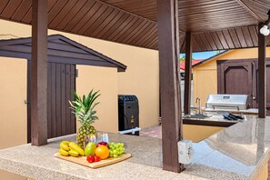 An outdoor kitchen area with a grill, a fruit and vegetable display, and a water dispenser. - Huge Luxury Heated Pool/Spa Villa w/ Game Room, Office, Exercise Area & More! (Tampa)