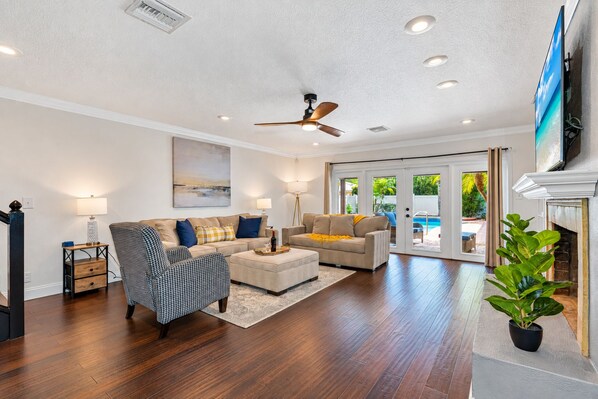 A spacious living room with a ceiling fan, two sofas, a coffee table, and a fireplace.