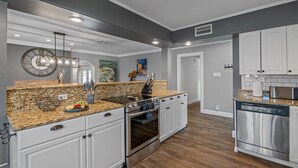 A modern kitchen with granite countertops, stainless steel appliances, and white cabinetry. - Huge Luxury Heated Pool/Spa Villa w/ Game Room, Office, Exercise Area & More! (Tampa)