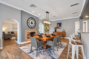 Un espace repas moderne avec une table en bois, des chaises grises et une cheminée.