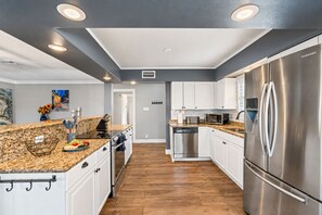 Une cuisine moderne dotée d’appareils électroménagers en acier inoxydable, de meubles blancs et d’un plan de travail en granit.
