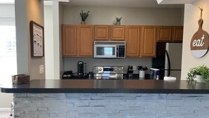 A kitchen with wooden cabinets, a built-in microwave, a stainless steel oven, and a black countertop. - Cozy, bright 2BD w/yard, close to DT-bikes avail! (Manassas)