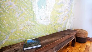 Eine hölzerne Bank, auf der ein Buch mit dem Titel "FLY FISH" liegt, vor einer Wand mit einer Karte.
