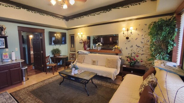 A living room with a sofa, coffee table, and a TV mounted on the wall. There is a kitchen area with a microwave and cabinets. - Downtown 1 Bedroom Duplex can Sleep 5 Close to Everything (Indianapolis)