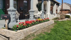 A building with a green door, white columns, and a flower bed with red and yellow flowers. - Downtown 1 Bedroom Duplex can Sleep 5 Close to Everything (Indianapolis)