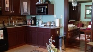 A kitchen with dark wooden cabinets, a microwave, and a sink. There is a dining table with a vase of flowers in the center. - Downtown 1 Bedroom Duplex can Sleep 5 Close to Everything (Indianapolis)