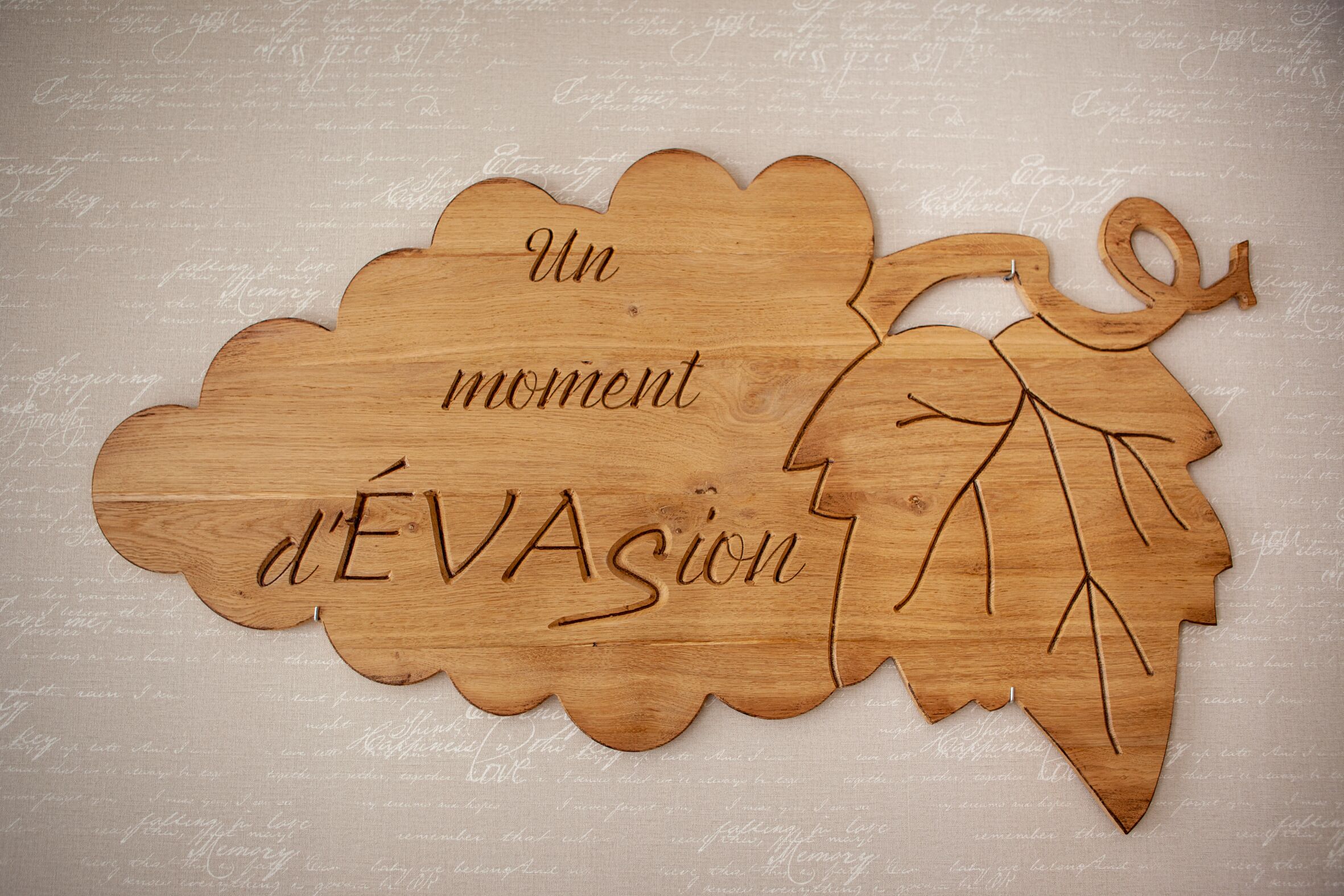 Een houten uitsnede met de tekst 'Un moment d'ÉVASION' op een gestructureerde achtergrond.