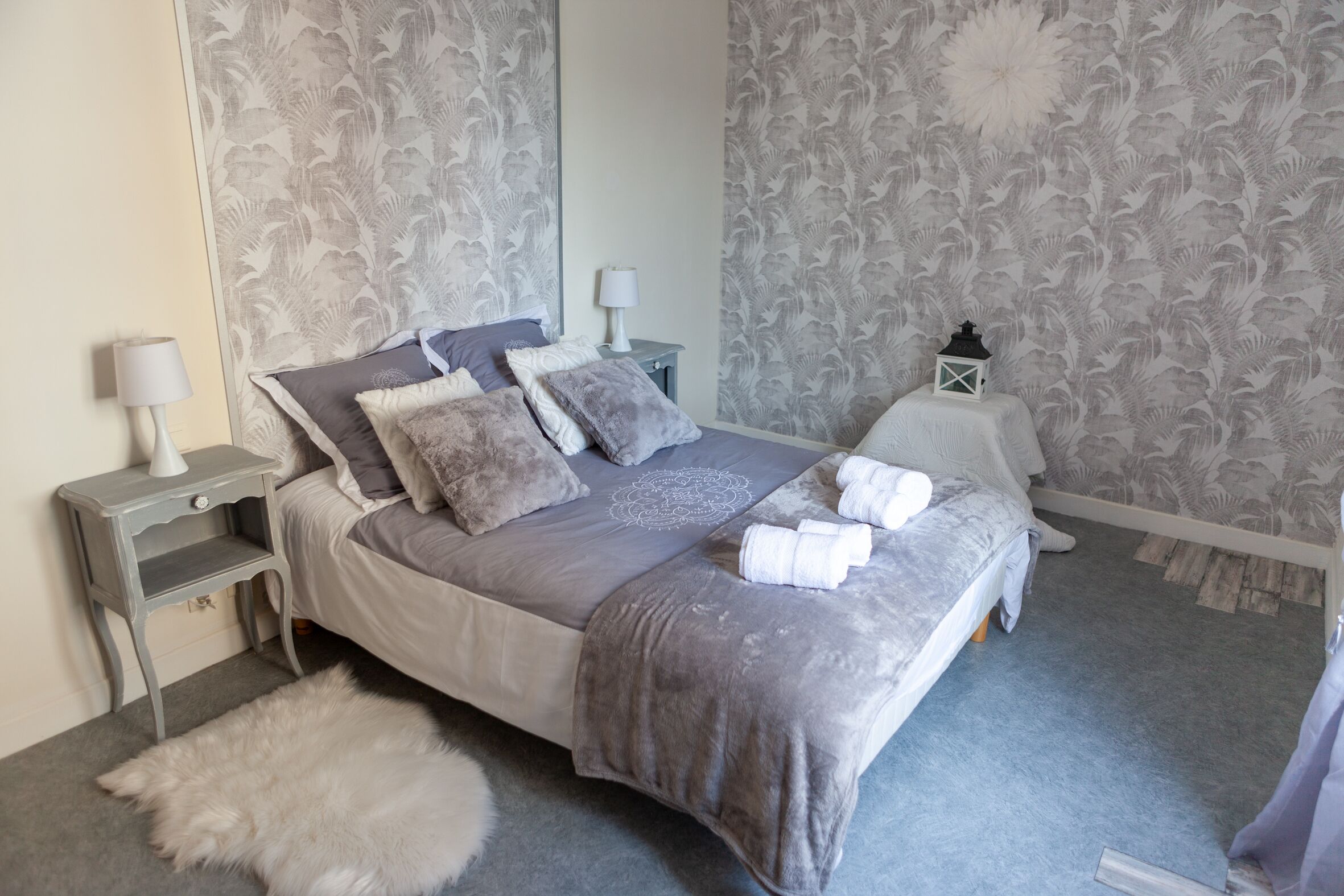 A neatly arranged bedroom with a bed, pillows, a fluffy rug, and a nightstand with a lamp.