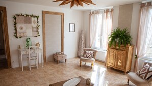 Una habitación bien iluminada con piso de madera, un escritorio blanco, una silla, un armario y una planta en maceta.