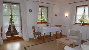 Een gezellige kamer met een eettafel, stoelen, een bank en een raam met gordijnen.