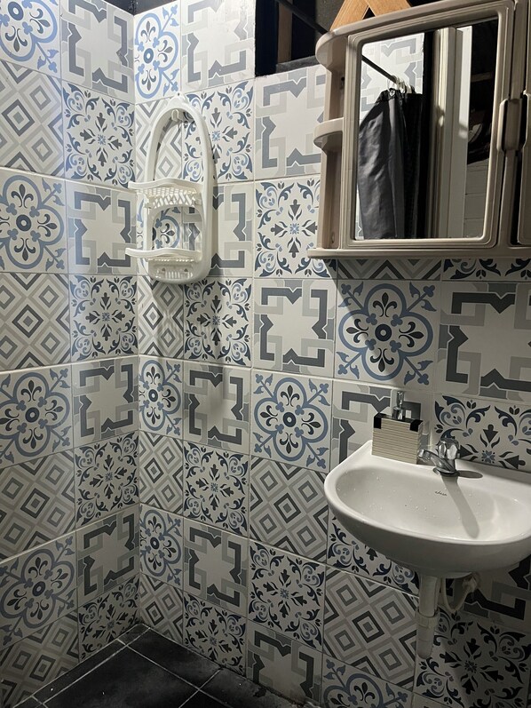 A bathroom with patterned tiles, a white sink, and a mirror.