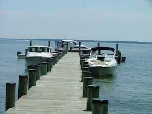 Guests can enjoy a serene waterfront experience with access to the calm waters and a variety of boats docked at the end of the pier.